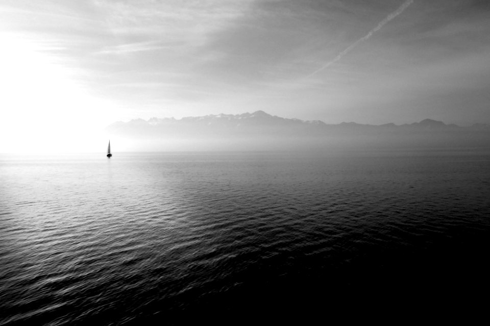 sailboat on calm body of water under white sky at daytime photo