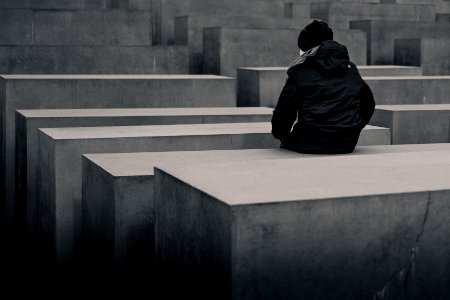 grayscale photo of woman sitting on concrete block photo