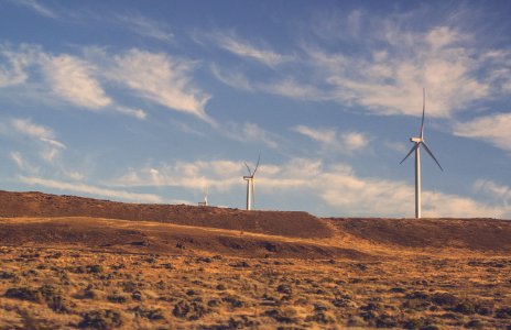 two gray wind turbines under cloudy blue sky during daytime photo