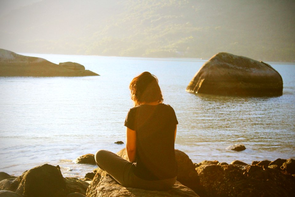 person sitting near body of water during daytime photo