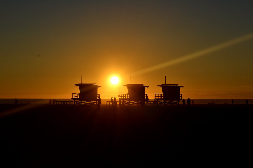 silhouette of three cottages on the beach