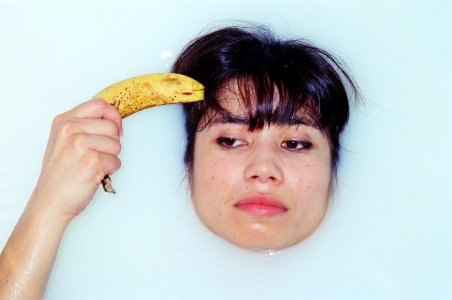 A woman holding a banana to her head while fully submerged in a bathtub. photo