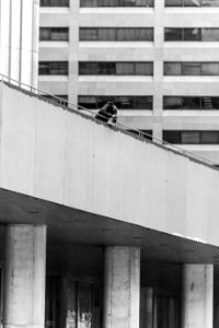 grayscaled photo of man leaning against bridge railing photo