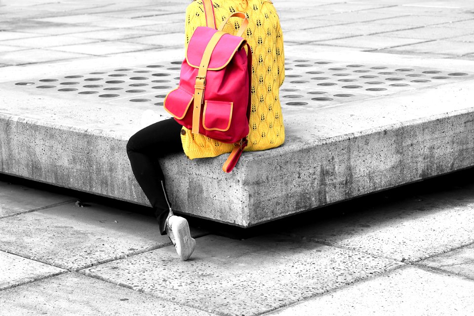 woman carrying pink backpack sitting on the edge concrete bracket