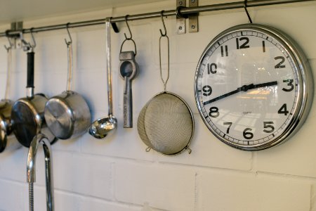 round white and gray stainless steel analog clock displaying 02:43 time near gray stainless steel saucepans hanging on wall photo