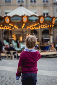 selective focus photography of boy standing in front of carousel photo