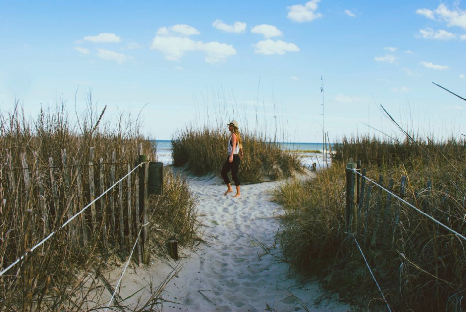 woman standing on pathway surrounded by tall grass at daytime photo