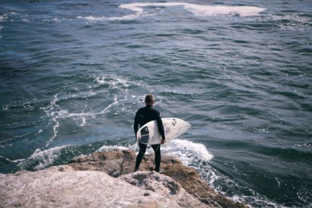 man holding surfboard standing in front of sea photo