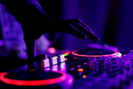 selective focus silhouette photography of man playing red-lighted DJ terminal photo