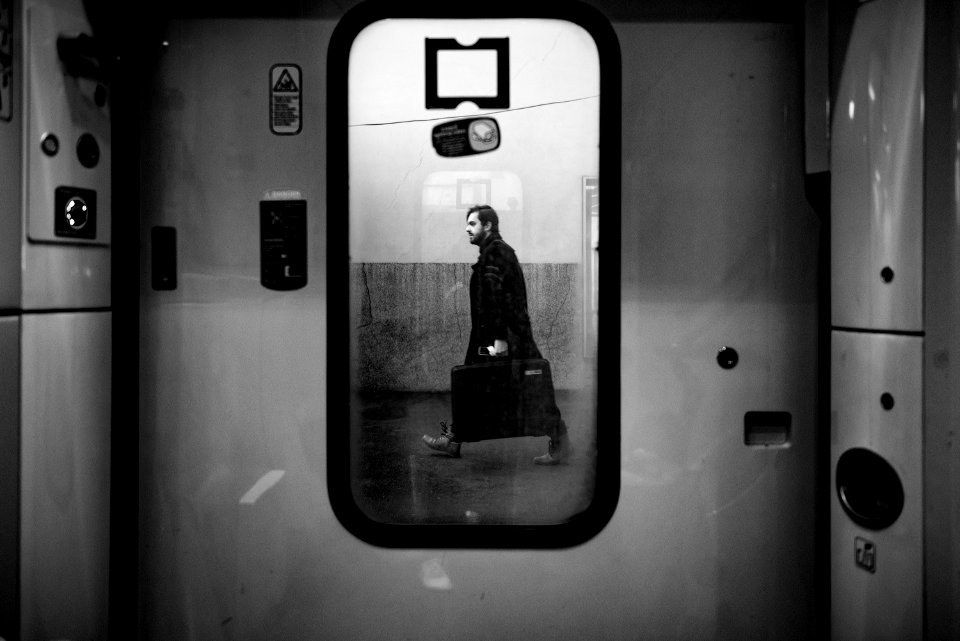 man walking outside train door in grayscale photo