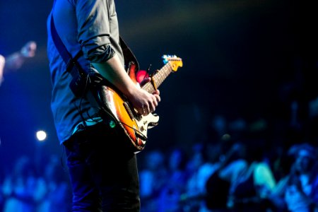 selective focus photography of man playing electric guitar on stage photo