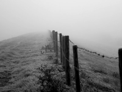 grayscale photo of wooden fence on grass field while fogging photo