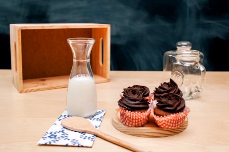 four cupcakes on brown coaster and milk jar photo