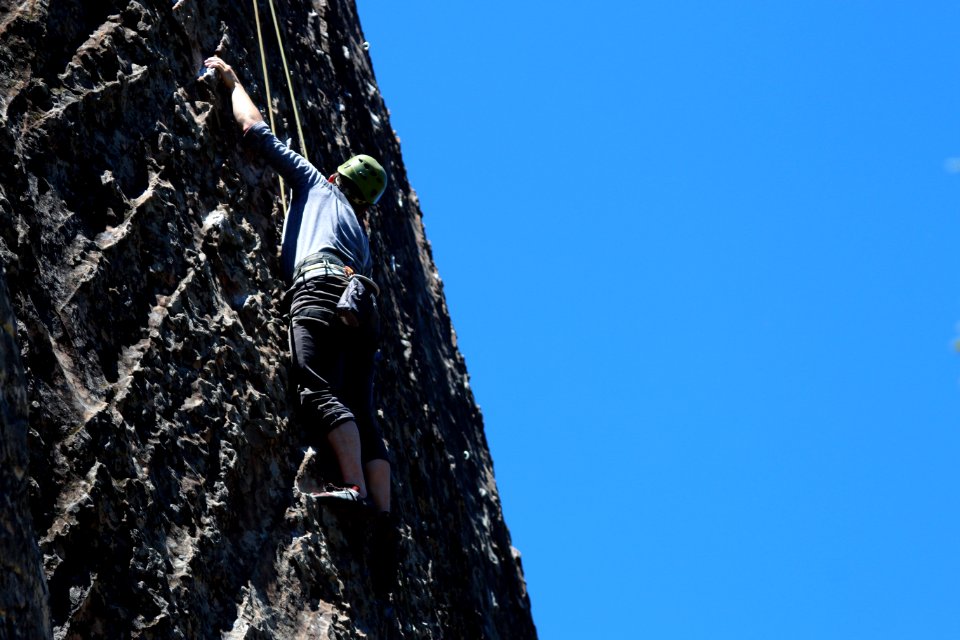 man performing wall climbing under clear sky
