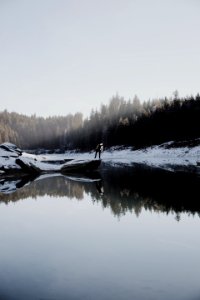 person beside lake near pine trees during daytime photo