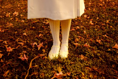 girl standing on grass wearing white dress and shoes during daytime photo