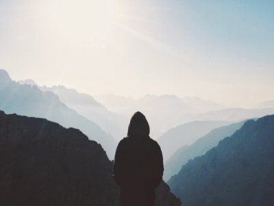 man in hoodie standing in front of the mountain photo