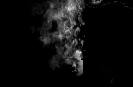 grayscale photography of man smoking cigarette