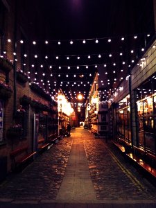photo of narrow street with light bulbs during night time photo