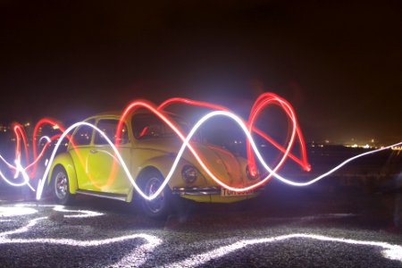 yellow Volkswagen Beetle in time lapse photography during night photo