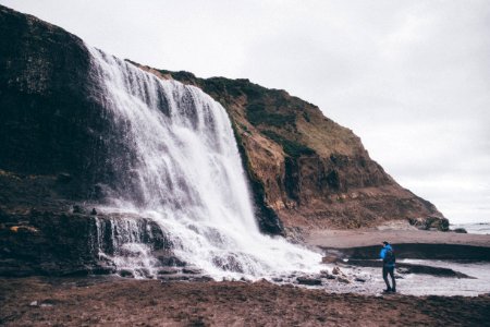 photo of man standing near waterfalls photo