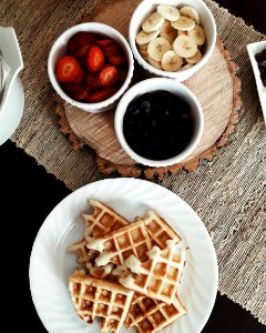 photo of waffles beside bowls of strawberries, banana, and black berries photo