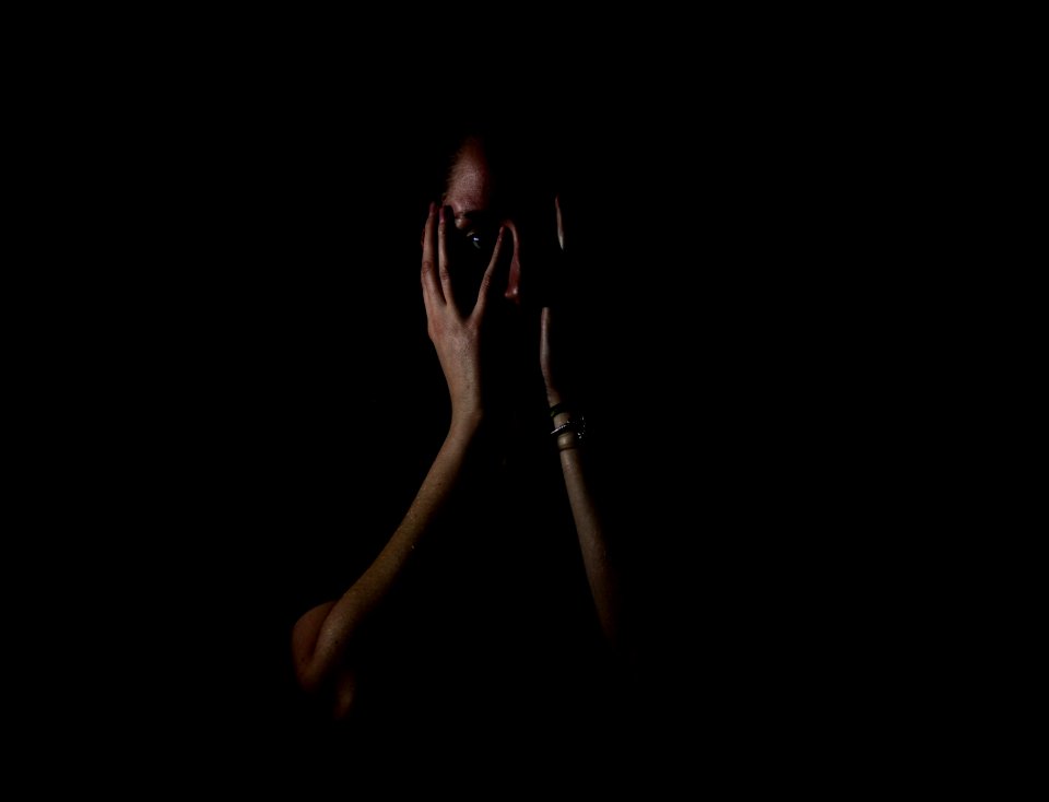 woman holding her face in dark room photo