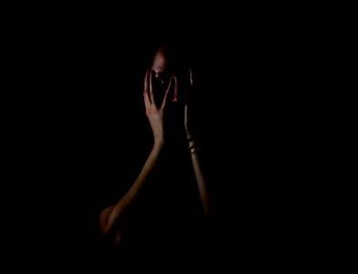 woman holding her face in dark room photo