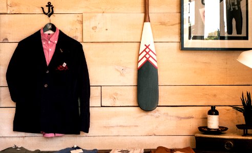 black jacket hanging on brown wooden wall beside boat paddle photo