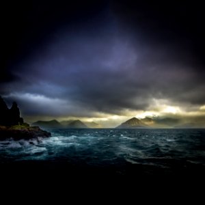 landscape photo of waters, mountains, and black clouds