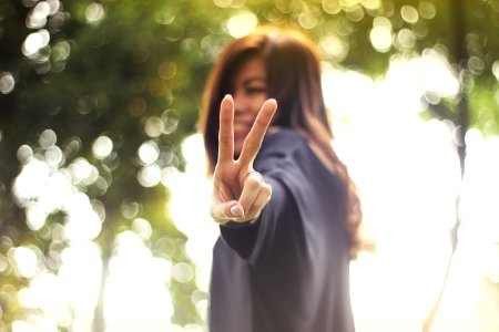 smiling woman making peace hand sign while standing photo