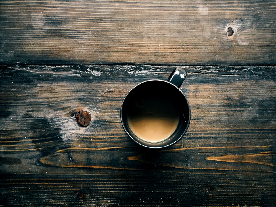 gray cup with brown liquid inside on top of table