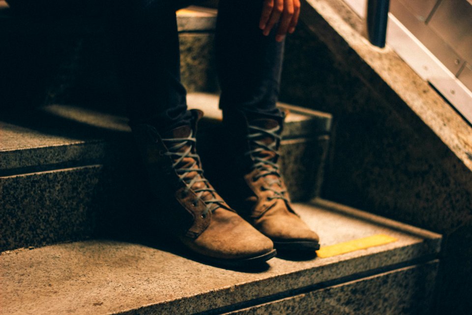 person wearing pair of brown lace-up boots with sitting on stairs