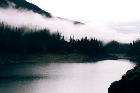 calm body of water surrounded by mountain and fogs photo