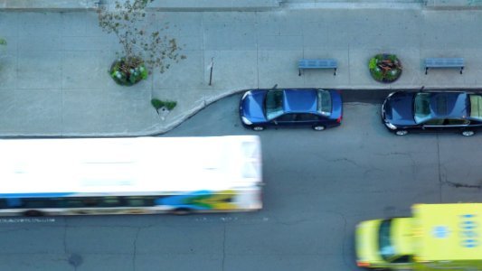 two blue parked vehicles near running bus and yellow-green truck aerial photography photo