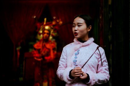 woman in pink sweatshirt holding stick shallow focus photography