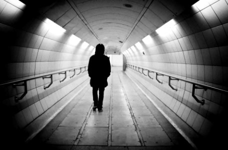woman in black coat walking on tunnel photo
