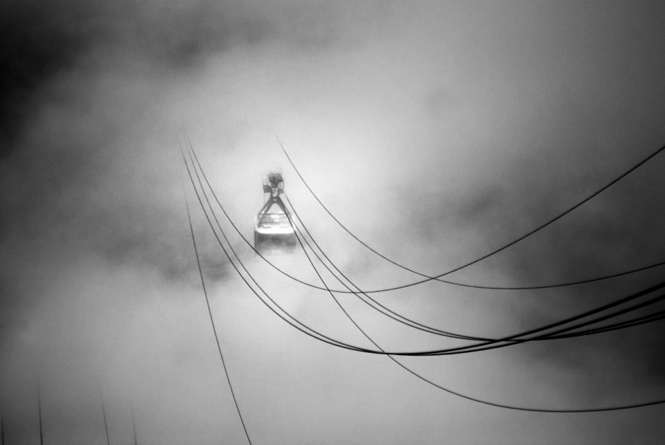grayscale photo of cable car in the midst of clouds