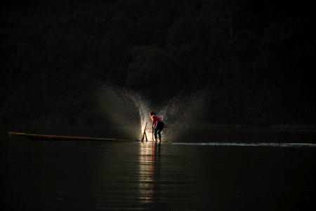 person standing on boat playing water photo