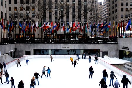 people ice skating on field surrounded by high-rise buildings photo