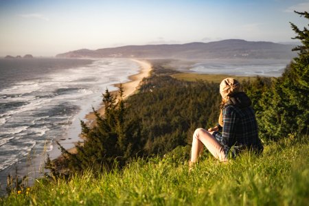 person sitting on hill near ocean during daytime photo