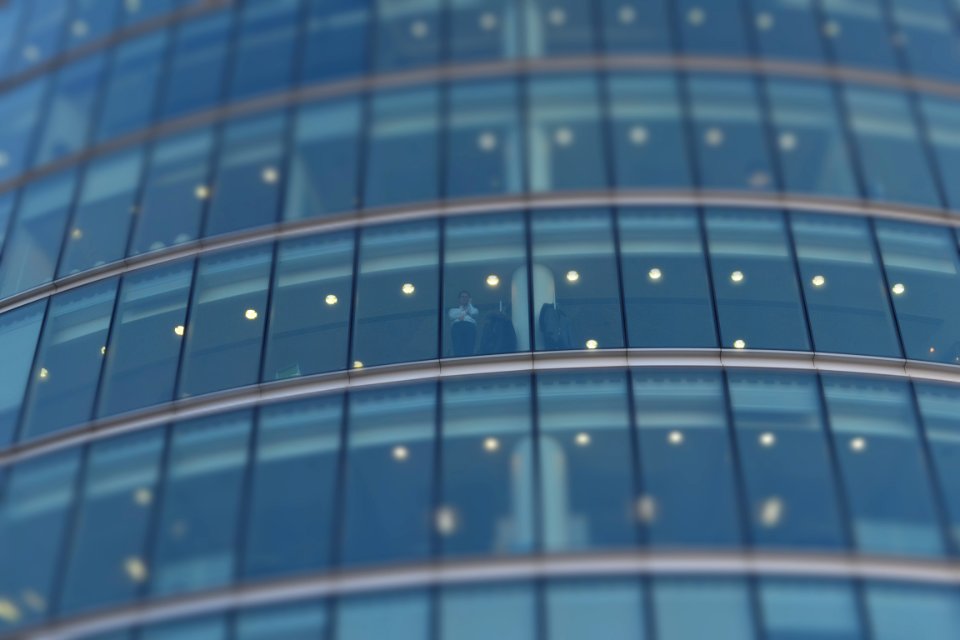 selective focus photograph of person standing near building glass curtain photo