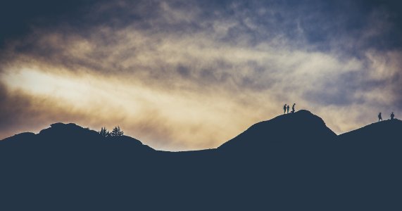 silhouette of people crossing a mountain photo