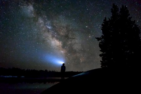 silhouette of man standing near body of water under night sky