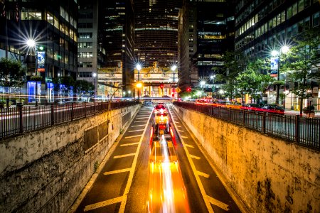 time lapse photography of vehicle passing on concrete road surround high-rise buildings during night time photo