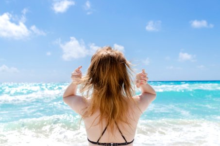 woman wearing black bra raising both arms facing towards the sea at daytime photo