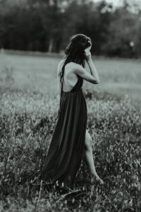 grayscale photography of woman wearing dress on grass field while standing photo