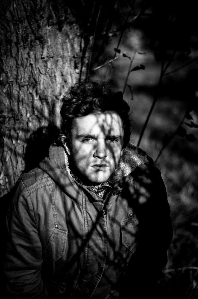 grayscale photo of man under tree