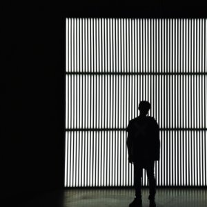 silhouette photo of a person standing near wall in dark room