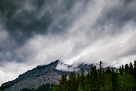gray rocky mountain near green trees under white clouds photo